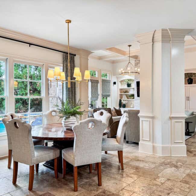 Bright living room featuring large windows, beige furniture, chandelier, and decorative accents creating a cozy and inviting atmosphere.