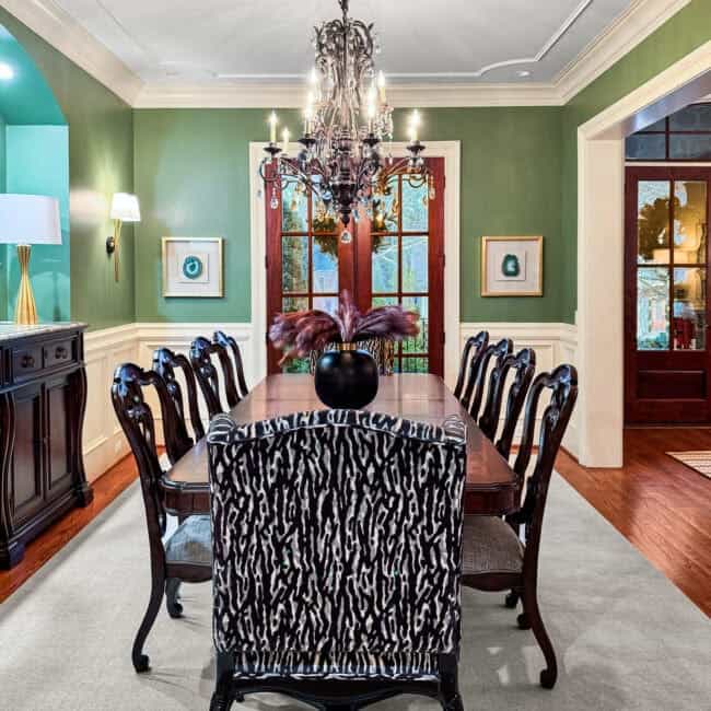 Charming dining room with chandelier, green walls, and wood furniture.