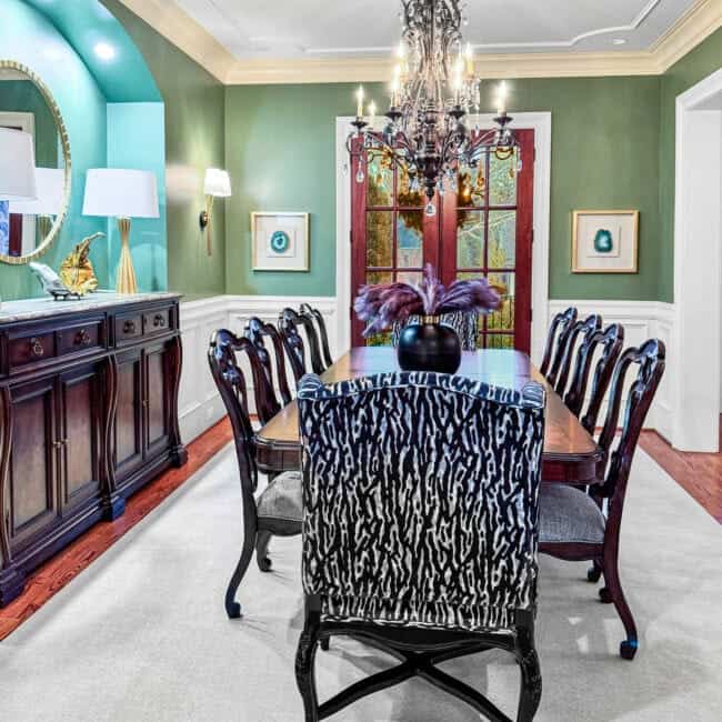 Charming dining room featuring a chandelier, green walls, and sophisticated decor.