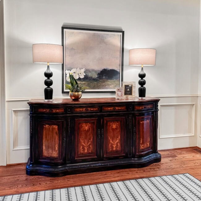 Sophisticated dark wood sideboard with lamps, framed artwork, and decor accents.