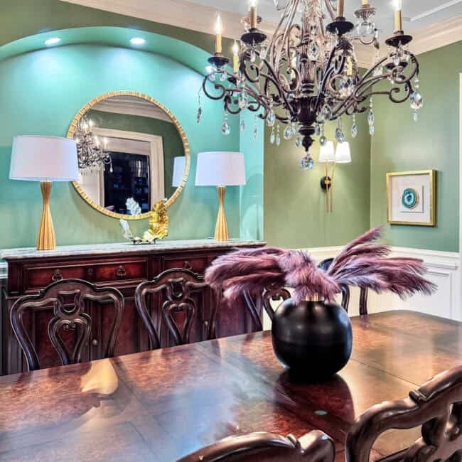 Chandelier with crystals hangs over wooden dining table and vintage chairs.