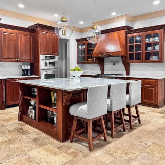 Stylish kitchen with rich wood cabinets, marble countertop island, and pendant lighting.