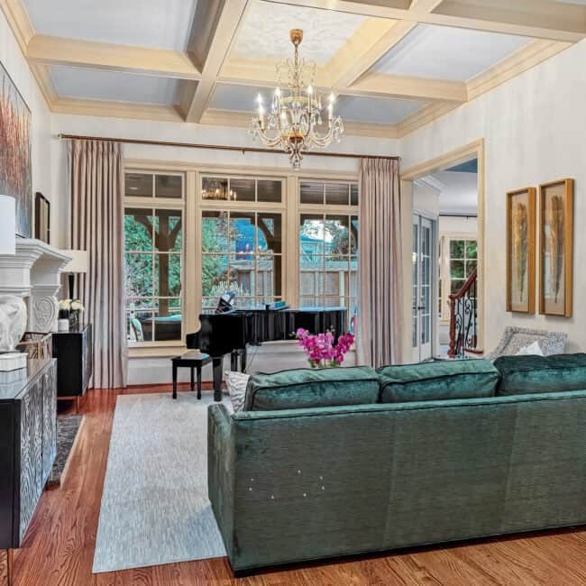 Bright living room with classic interior design, featuring a grand piano, art decor, and lush views outside.