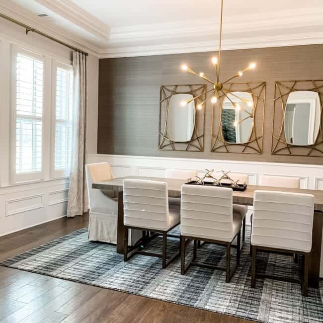 Bright, airy dining space with sophisticated wallpaper, framed mirrors, and chic furniture design.