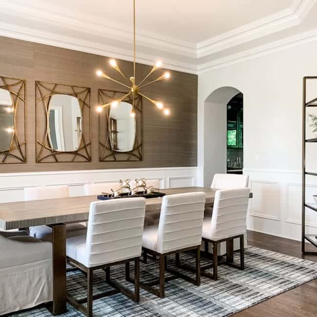 Stylish dining area featuring white chairs, wooden table, and decorative wall mirrors.