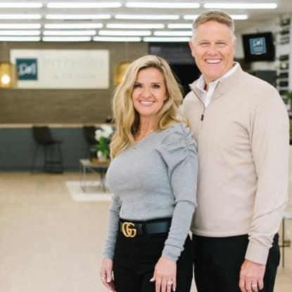 Smiling man and woman standing together in an office environment, showcasing a professional and friendly atmosphere.
