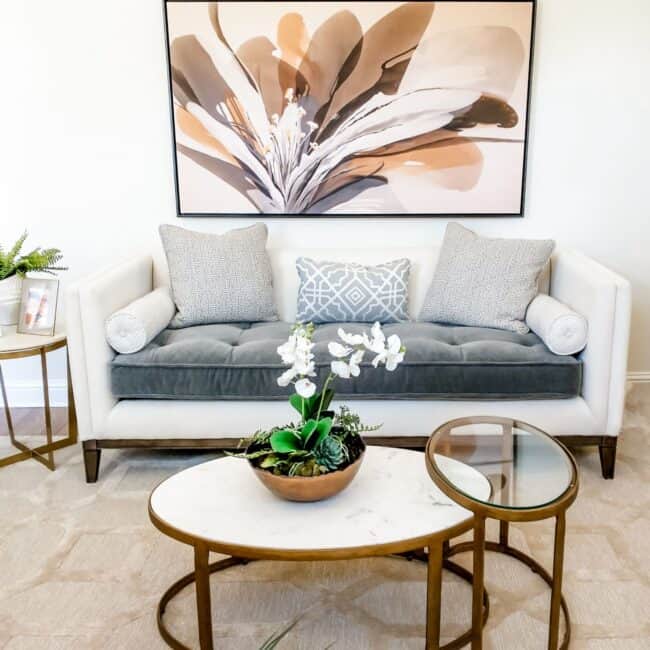 Elegant living room decor with abstract flower art and plush pillows.