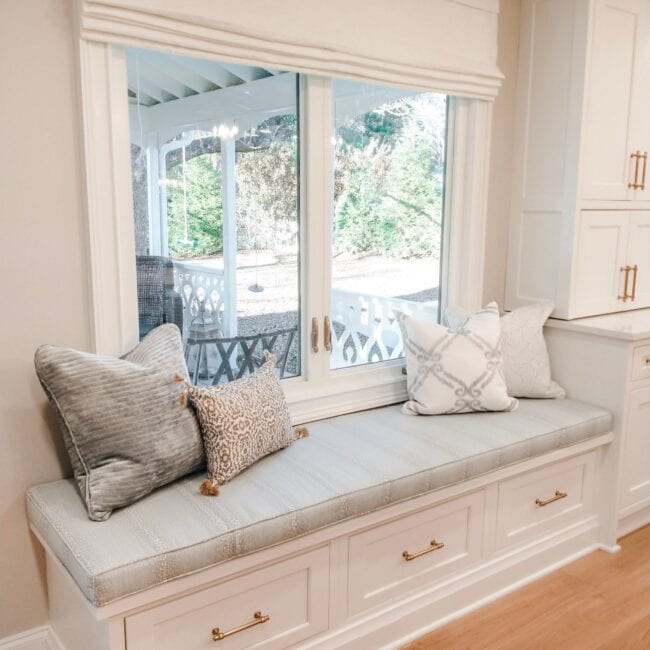 Bright window nook with cozy seating and decorative cushions, enhancing home decor and interior comfort.