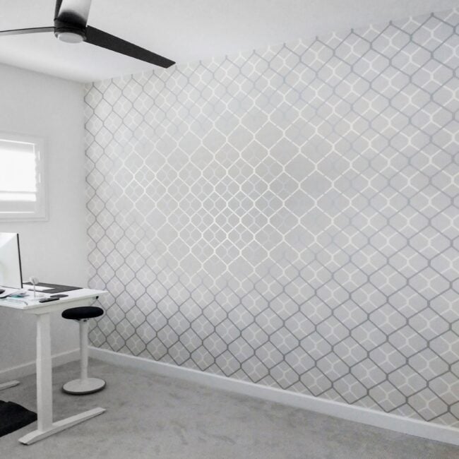 Bright white home office with patterned wall, ceiling fan, and ergonomic desk setup.