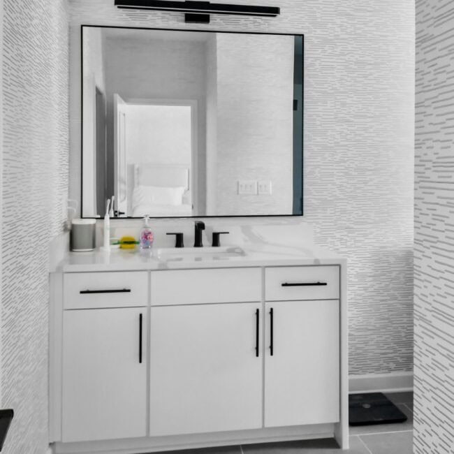 Contemporary bathroom with sleek vanity, large mirror, and stylish wall patterns.