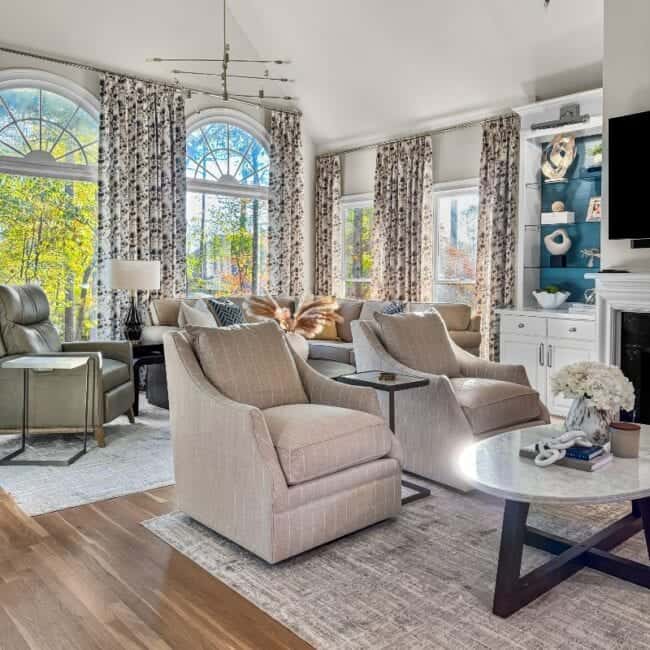 Bright and stylish living room with large arched windows, elegant curtains, and comfortable seating arrangements.
