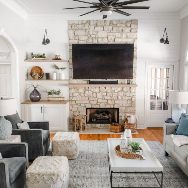 Bright living room featuring a stone fireplace, large windows, and modern furniture for a welcoming.