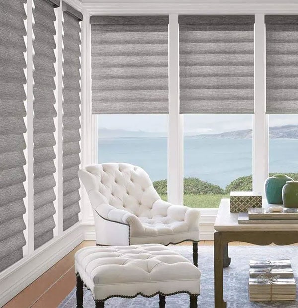 Bright sunroom featuring gray textured roller blinds and ocean view, perfect for relaxing and decor.