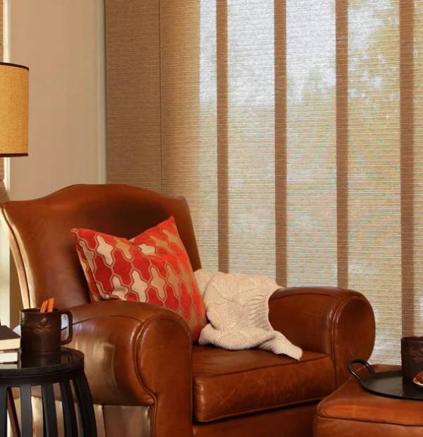 Comfortable leather armchair with decorative pillows and blanket in a warm living room setting.