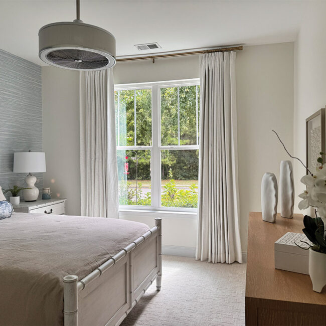 Bright bedroom with large window, white curtains, and modern decor.