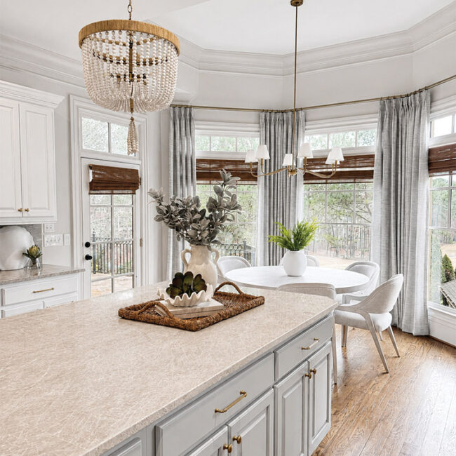 Elegant kitchen with large windows, white cabinets, and a cozy dining nook.