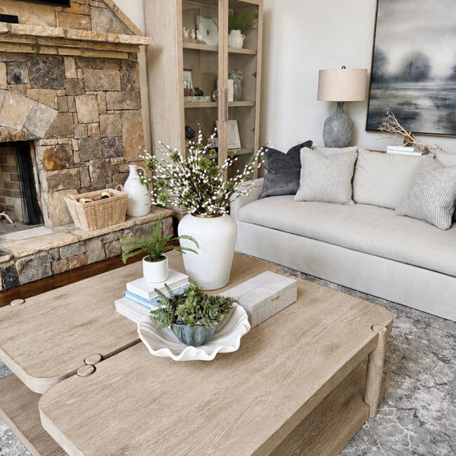Living room with stone fireplace, beige sofa, and wooden coffee table.