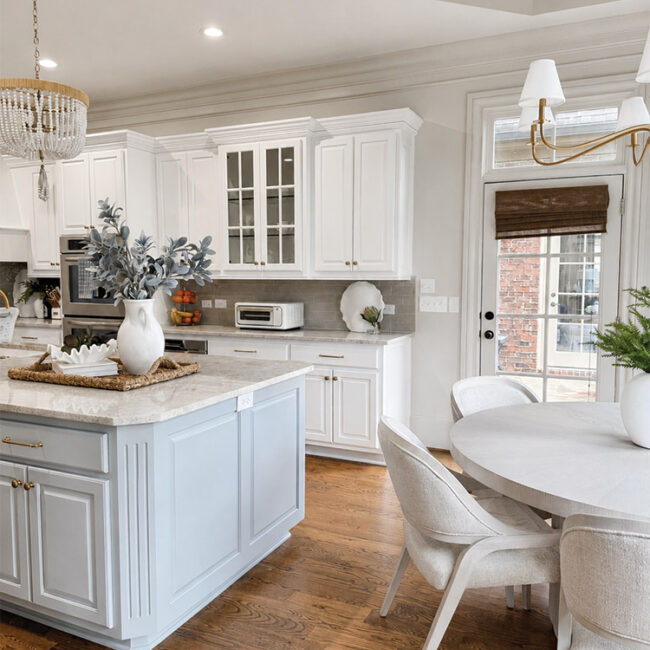 Bright white kitchen with island, dining table, and large window.