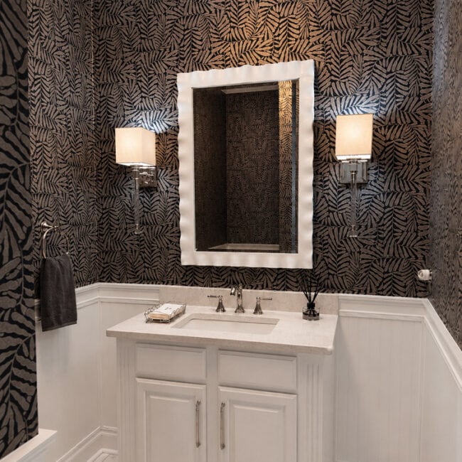Stylish bathroom with patterned wallpaper, white vanity, and wall-mounted lights.