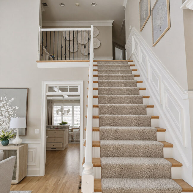 Interior view of a staircase with beige carpet and white railings in a bright home.