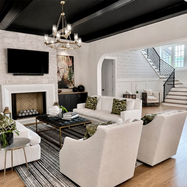 Bright living room with white sofas, black accents, and a fireplace.