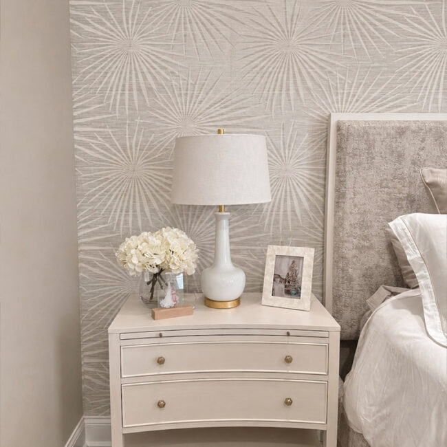White bedroom nightstand with lamp, flowers, and photo frame.