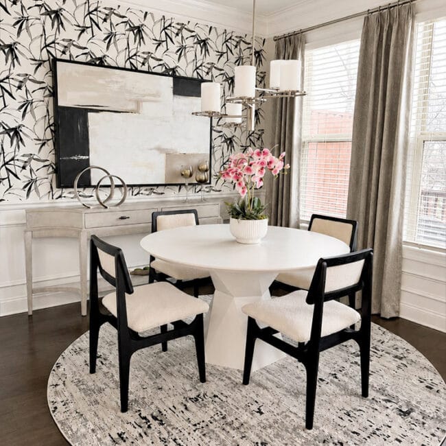 Stylish dining room with round table, black chairs, floral centerpiece, and abstract wall art.