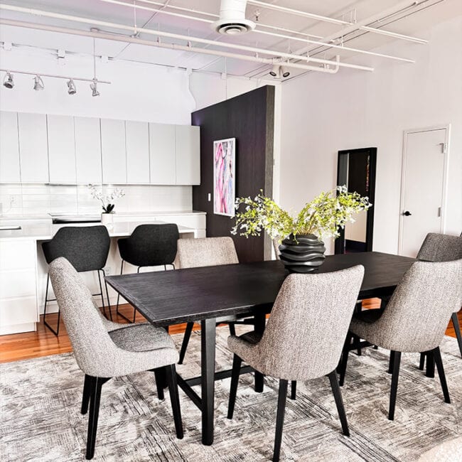 Contemporary dining room with black table, gray chairs, and artwork on the wall.