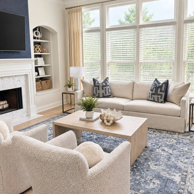 Spacious living room with large windows, cozy sofa, armchair, and fireplace.