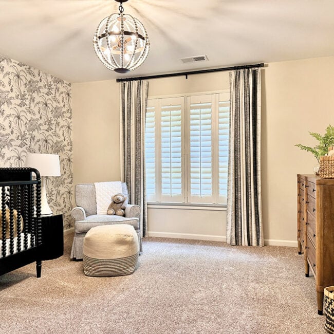 Bright nursery with crib, armchair, dresser, and window with curtains.