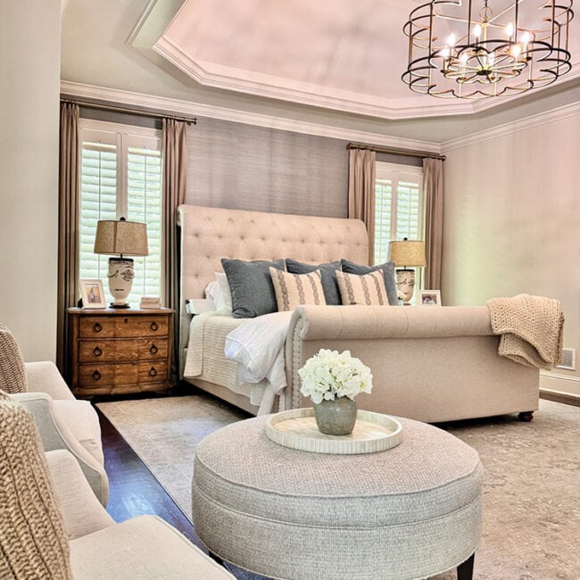 Spacious bedroom with tufted headboard, beige furniture, and soft lighting.