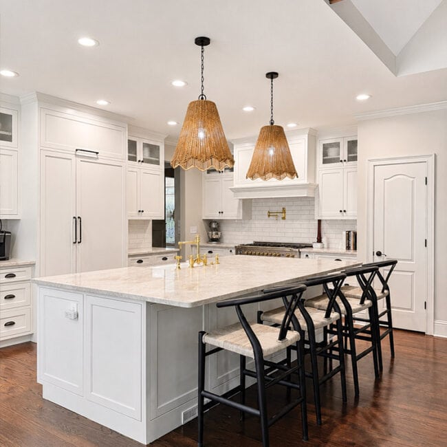 Bright modern kitchen with white cabinets, island, and pendant lighting.